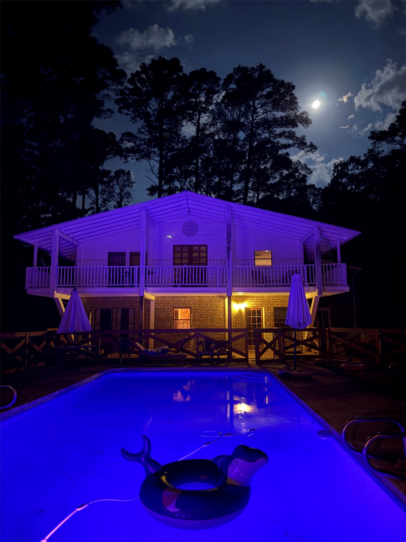 363 Porter Road Bastrop, TX 78602 - Photo 1 of 37 A spacious backyard pool area overlooks the illuminated two-story home under a starry night sky.