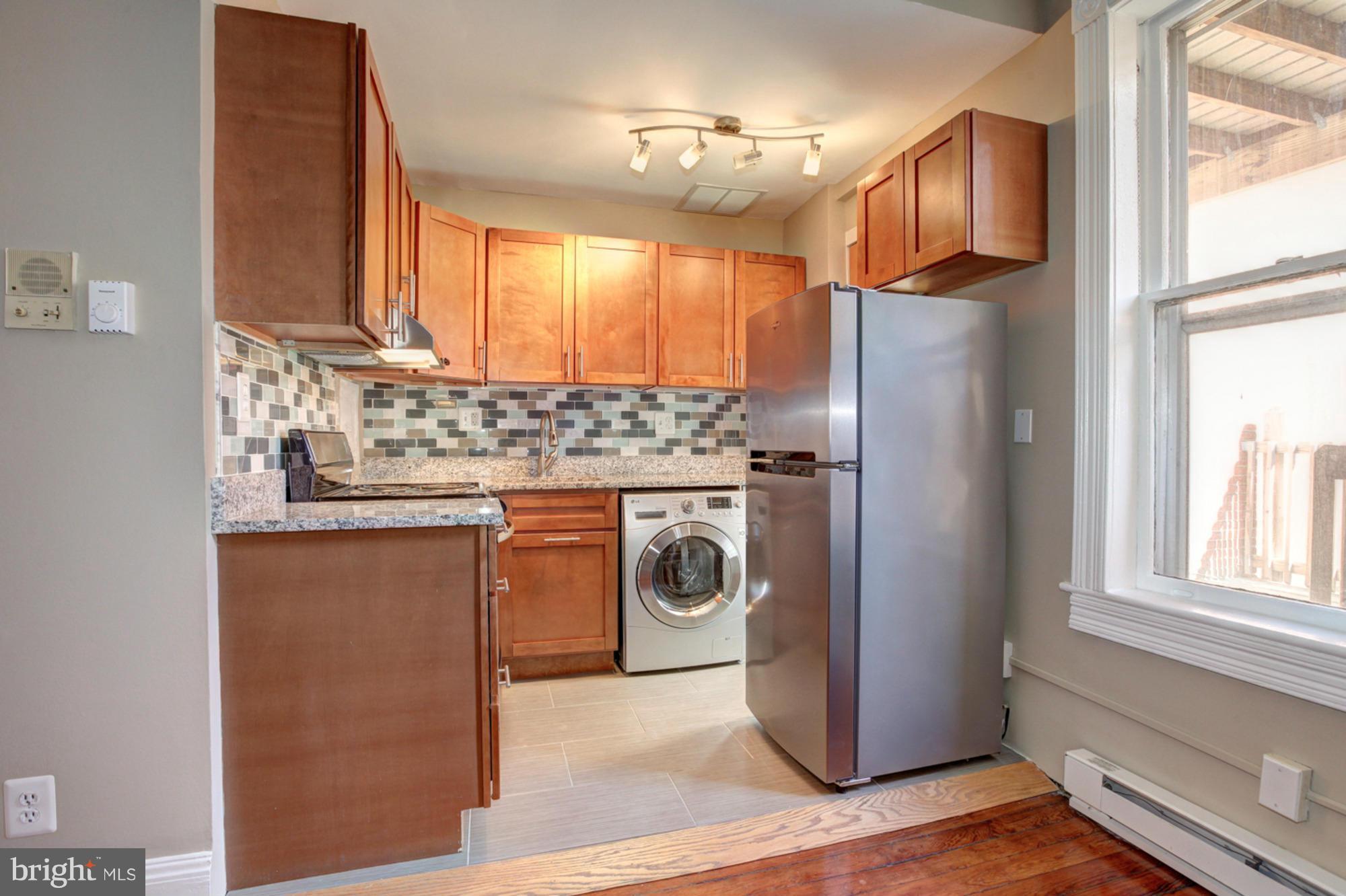 1739 19th Street Northwest Washington, DC 20009 - Photo 11 of 20 a kitchen with stainless steel appliances granite countertop a refrigerator a sink a stove and white cabinets with wooden floor