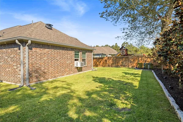 a view of yard with brick wall and a large tree
