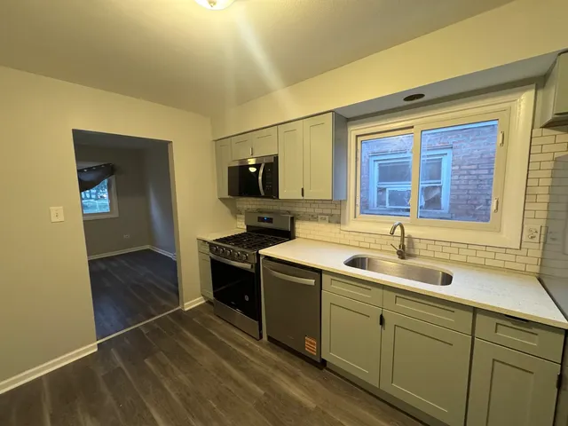 a kitchen with a sink cabinets stainless steel appliances and a window