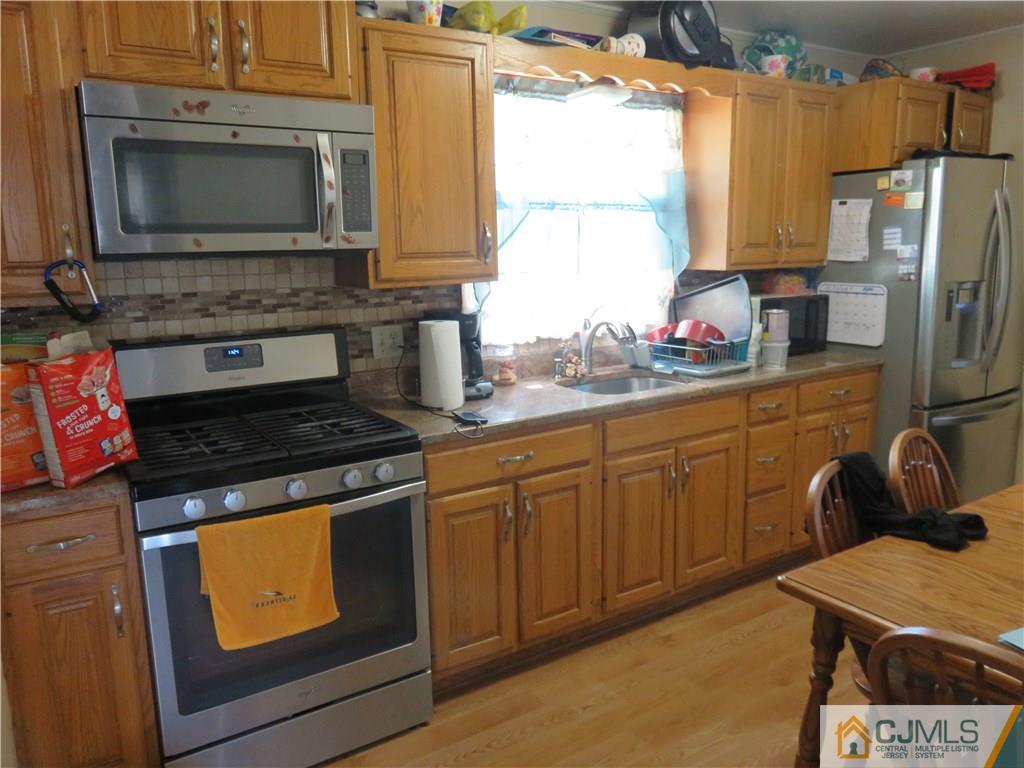 12 Pennington Road New Brunswick, NJ 08901 - Photo 5 of 10 a kitchen with stainless steel appliances a stove a microwave sink and cabinets