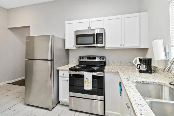 a kitchen with granite countertop a refrigerator stove and sink