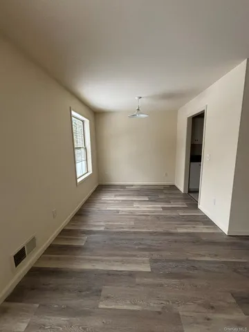 a view of empty room with window and wooden floor