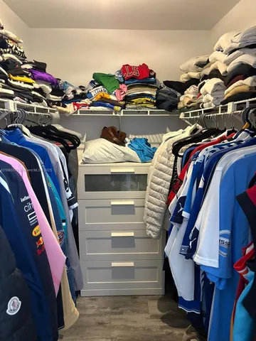a view of walk in closet with clothes and shoes