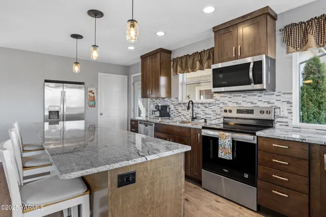 a kitchen with stainless steel appliances granite countertop a stove a sink and a microwave