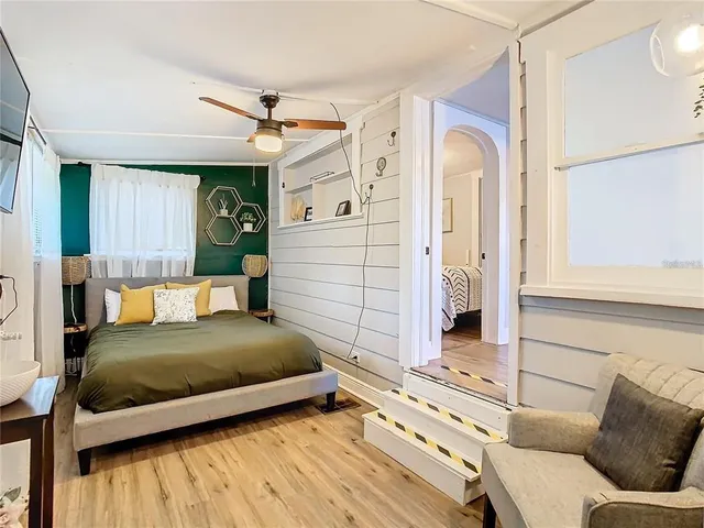 a bedroom with a bed and a dresser with wooden floor