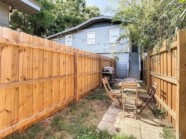 a backyard of a house with chairs and wooden fence