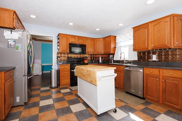 a kitchen with stainless steel appliances granite countertop a refrigerator a sink a stove top oven and wooden floor