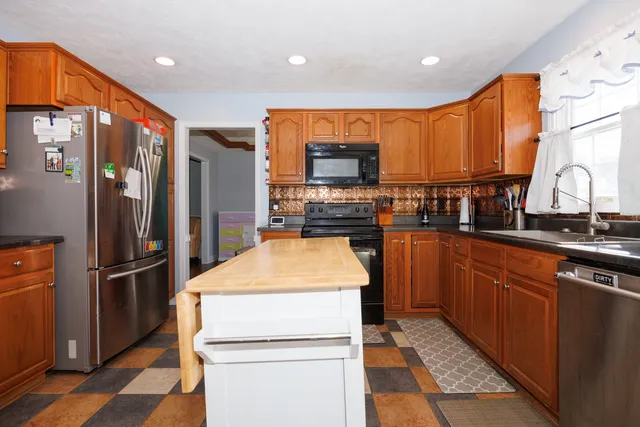 a kitchen with stainless steel appliances kitchen island granite countertop a refrigerator and a sink