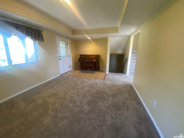 83 Canterbury Circle Logan, UT 84321 - Photo 9 of 23 Unfurnished living room with carpet floors and a raised ceiling