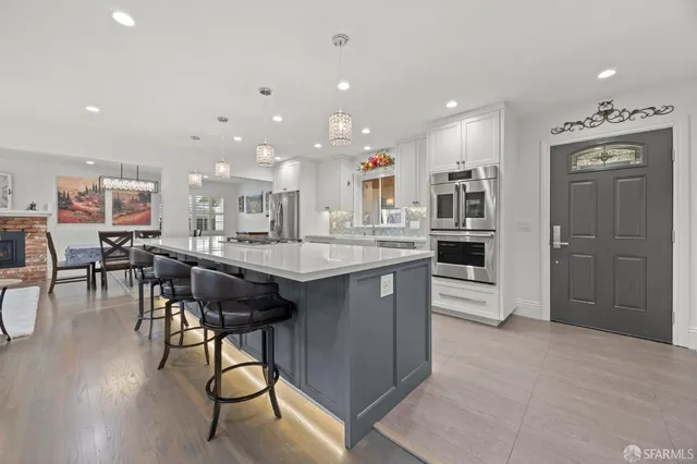 a view of a kitchen counter top space a sink stainless steel appliances and chandelier