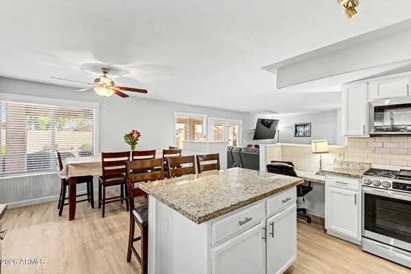 a open kitchen with granite countertop a stove dining table chairs and a fireplace