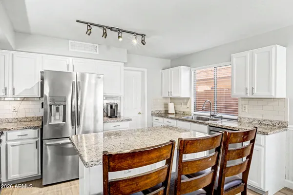 a kitchen with granite countertop a refrigerator a stove and white cabinets