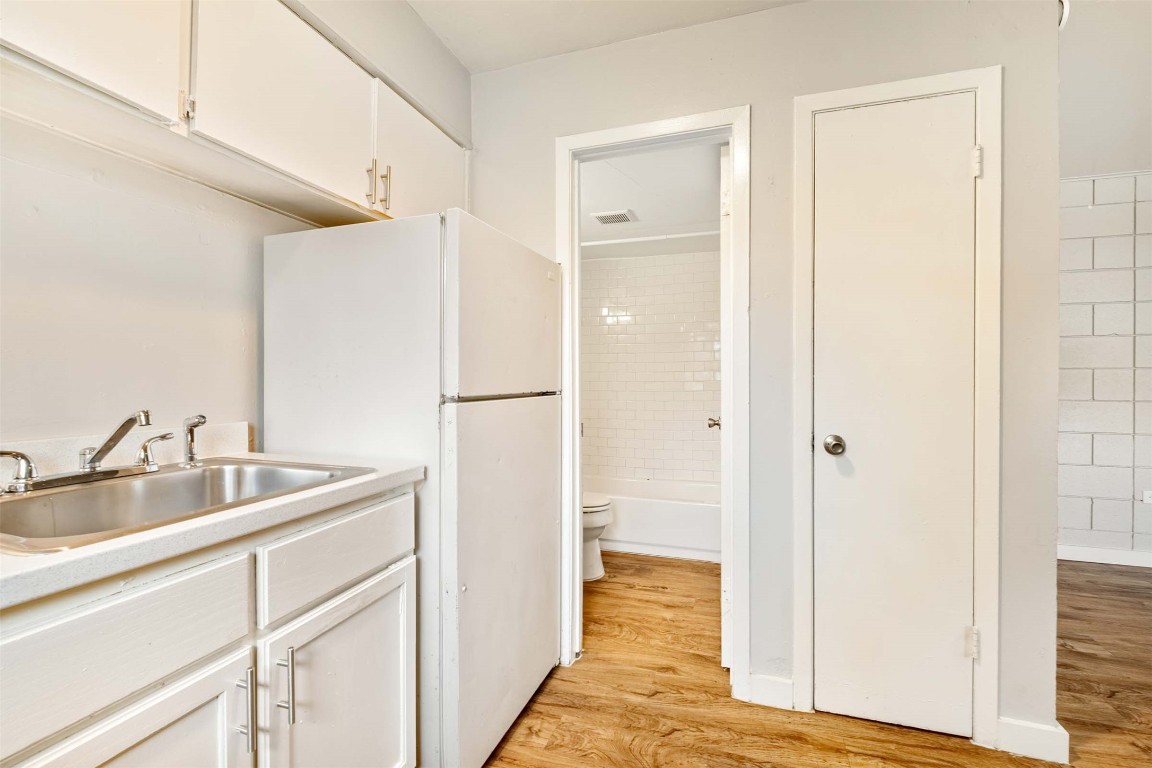 903 Springdale Road, Unit E Austin, TX 78702 - Photo 9 of 16 Kitchen with white cabinetry, light wood-style floors, freestanding refrigerator, and light countertops