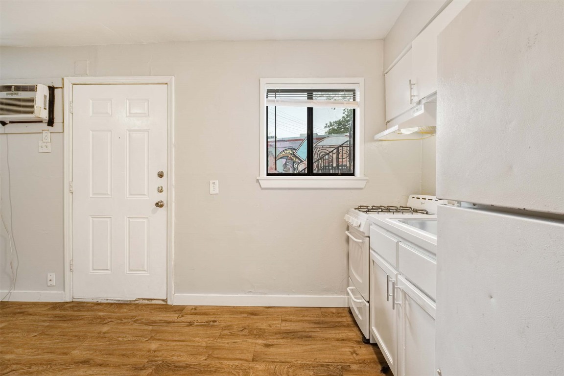 903 Springdale Road, Unit E Austin, TX 78702 - Photo 10 of 16 Kitchen featuring white cabinetry, white appliances, light wood-type flooring, under cabinet range hood, and light countertops