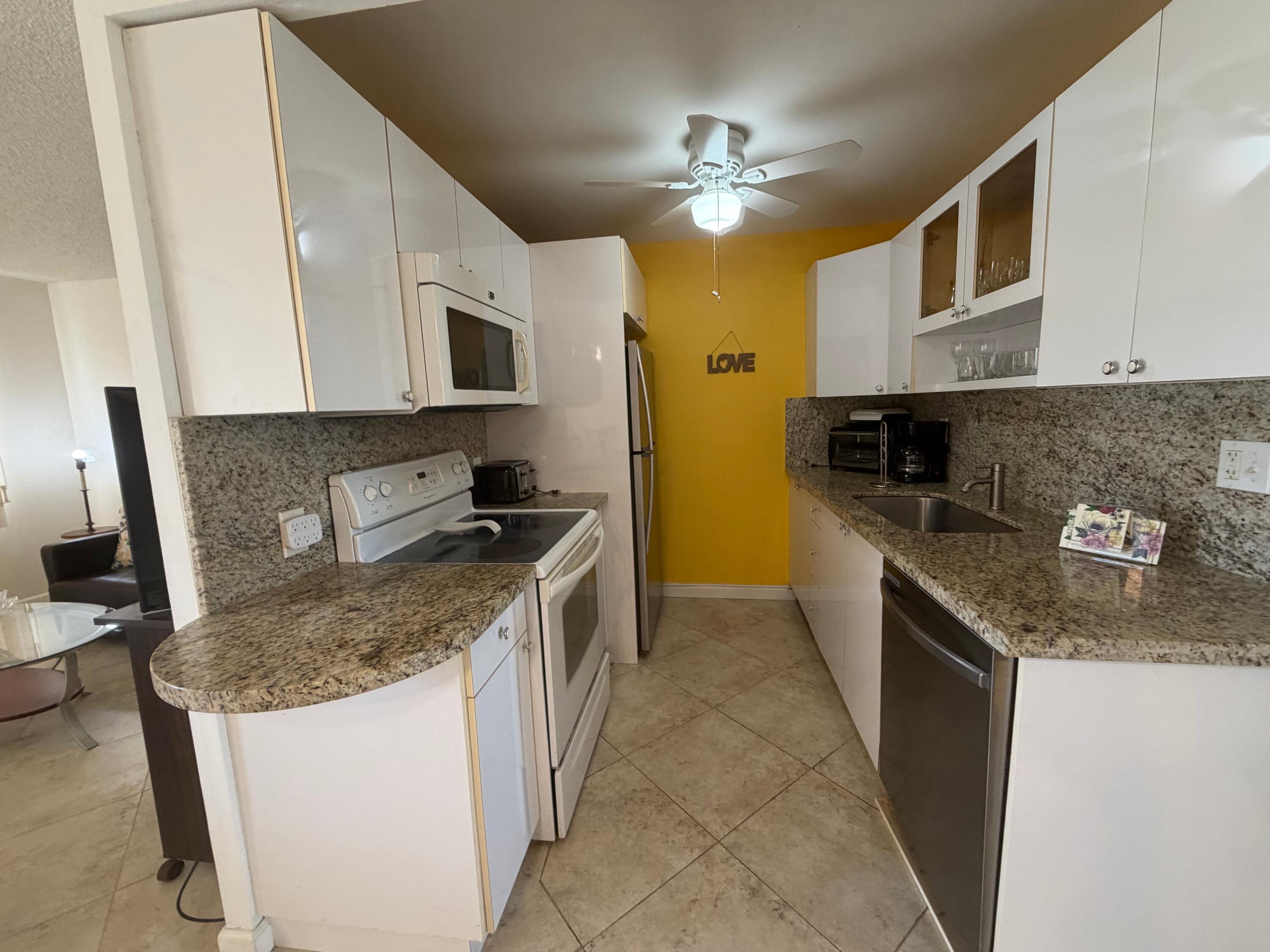 3058 Ainslie Drive, Unit 3058D Boca Raton, FL 33434 - Photo 3 of 13 a kitchen with stainless steel appliances granite countertop a sink stove and refrigerator