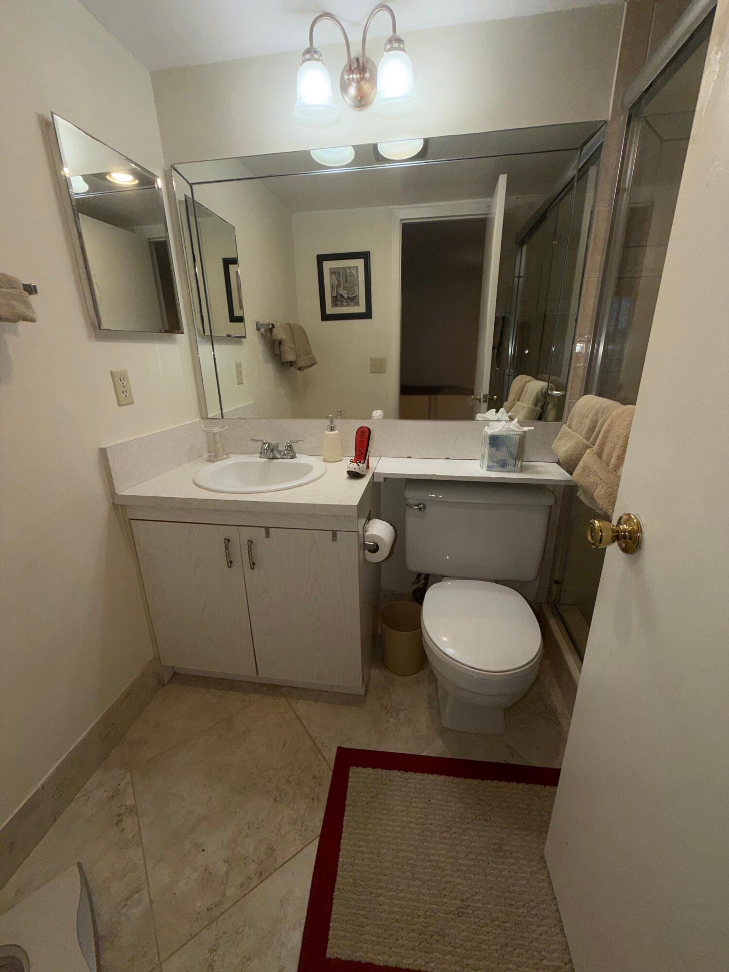 3058 Ainslie Drive, Unit 3058D Boca Raton, FL 33434 - Photo 4 of 13 a bathroom with a toilet sink and mirror