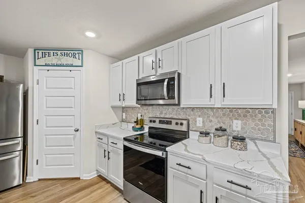 a kitchen with white cabinets and stainless steel appliances