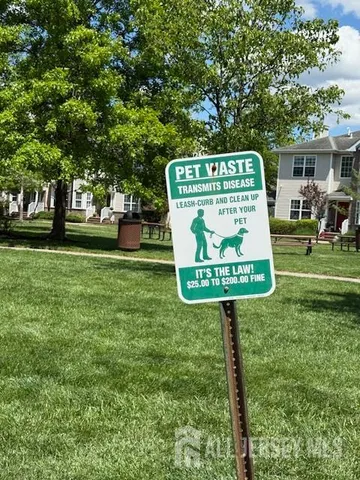 a sign that is sitting in the grass near a house