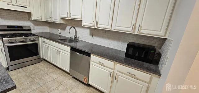 a kitchen with granite countertop white cabinets and stainless steel appliances