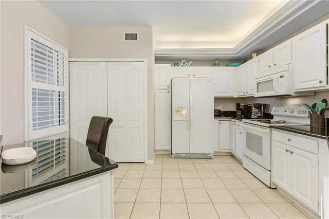 a kitchen with stainless steel appliances granite countertop a refrigerator sink and white cabinets