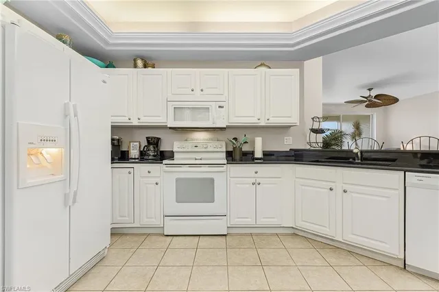 a kitchen with white cabinets a sink and appliances