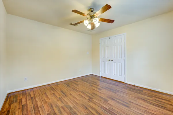 an empty room with wooden floor and a ceiling fan