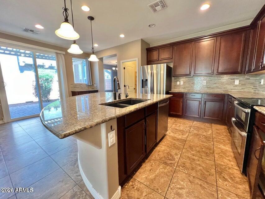 3886 East Rawhide Street Gilbert, AZ 85296 - Photo 11 of 52 a kitchen with stainless steel appliances granite countertop a sink counter space cabinets and a large window