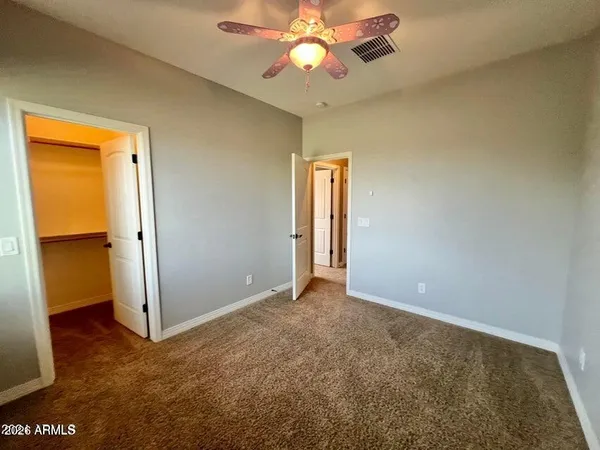 an empty room with closet and a chandelier fan