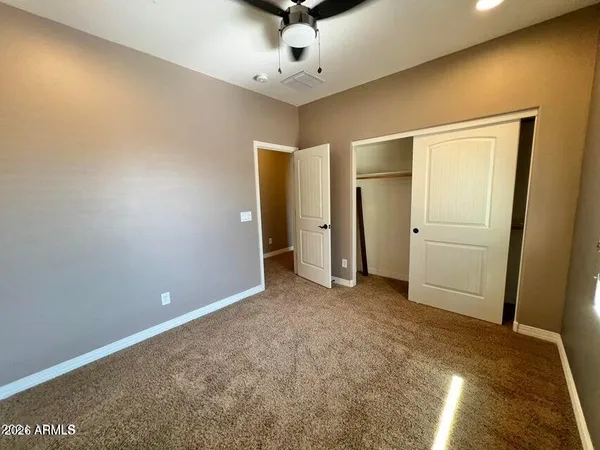 an empty room with closet and a ceiling fan