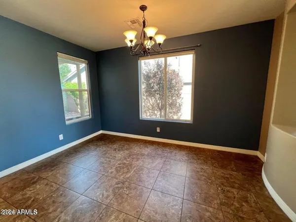 a view of an empty room with window and chandelier fan