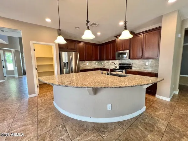 a view of a kitchen with kitchen island a large counter space a sink appliances and cabinets