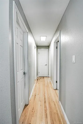 a view of a hallway with wooden floor and a bathroom