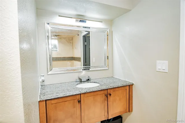 a bathroom with a granite countertop sink and a mirror