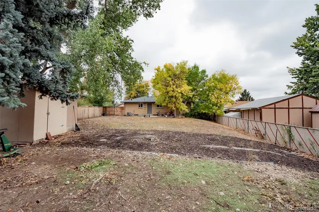 a view of a backyard with large trees and wooden fence