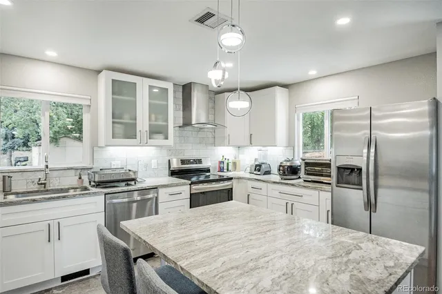 a kitchen with granite countertop a sink stainless steel appliances and window