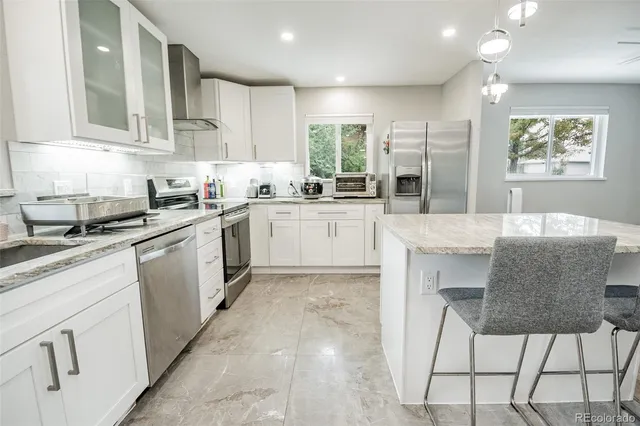 a kitchen with stainless steel appliances granite countertop a stove top oven a sink a dining table and chairs