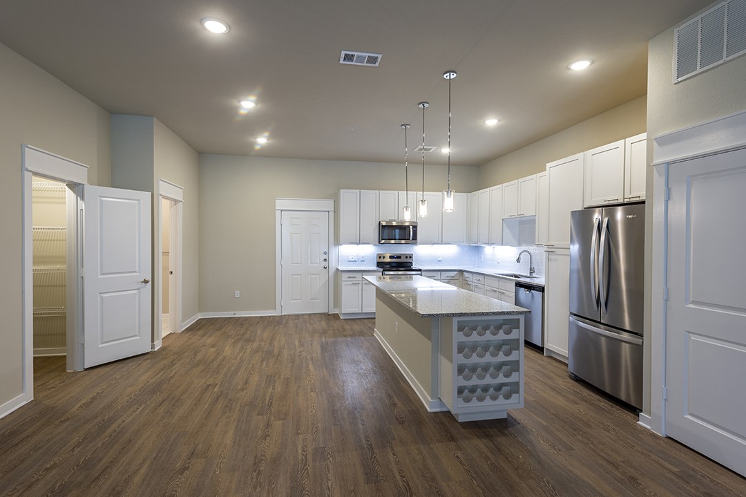 1724 Partnership Way, Unit 2102 Katy, TX 77449 - Photo 32 of 33 a kitchen with kitchen island wooden floors appliances and cabinets