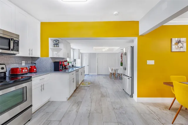 a kitchen with stainless steel appliances granite countertop a sink dishwasher stove and white cabinets