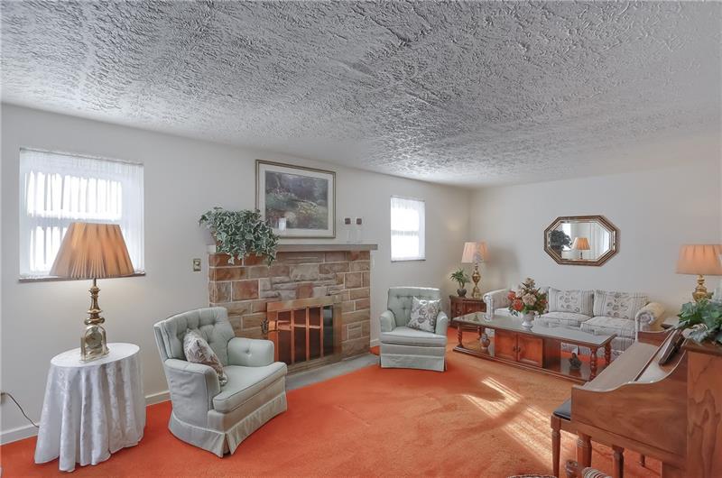 This sun filled space features a stone fireplace and large windows. 