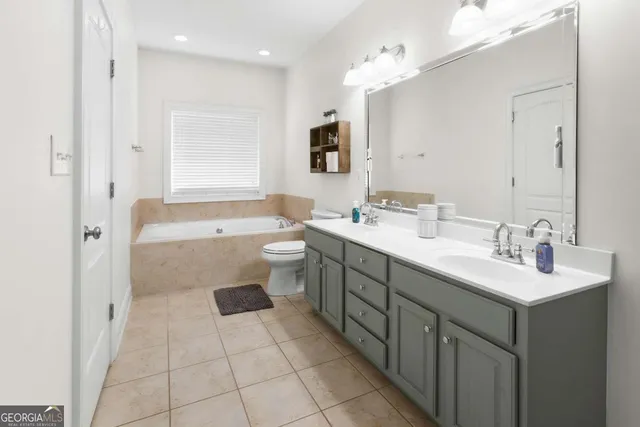 a bathroom with a sink vanity granite tub shower and a mirror