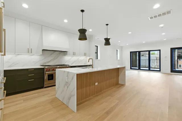 a large kitchen with granite countertop a large counter top a sink stainless steel appliances and cabinets