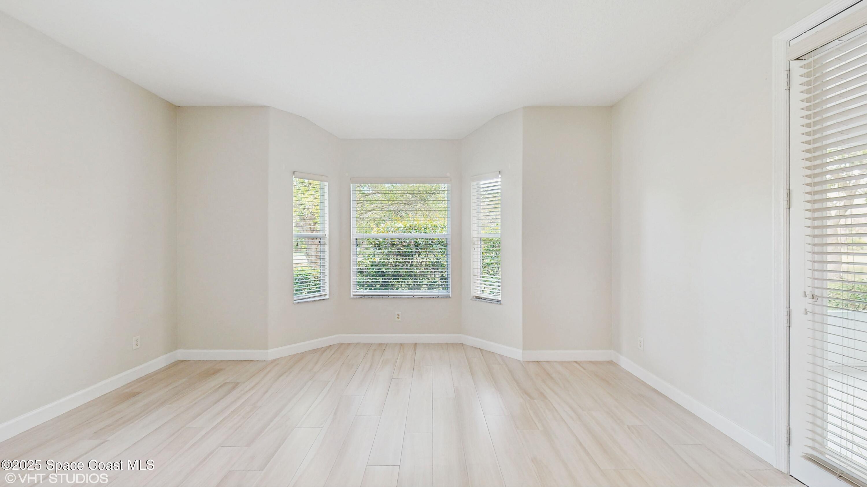 652 Hatteras Court Southwest Vero Beach, FL 32968 - Photo 16 of 48 an empty room with wooden floor and windows