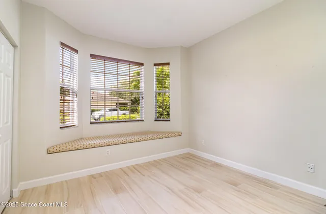 an empty room with wooden floor and windows