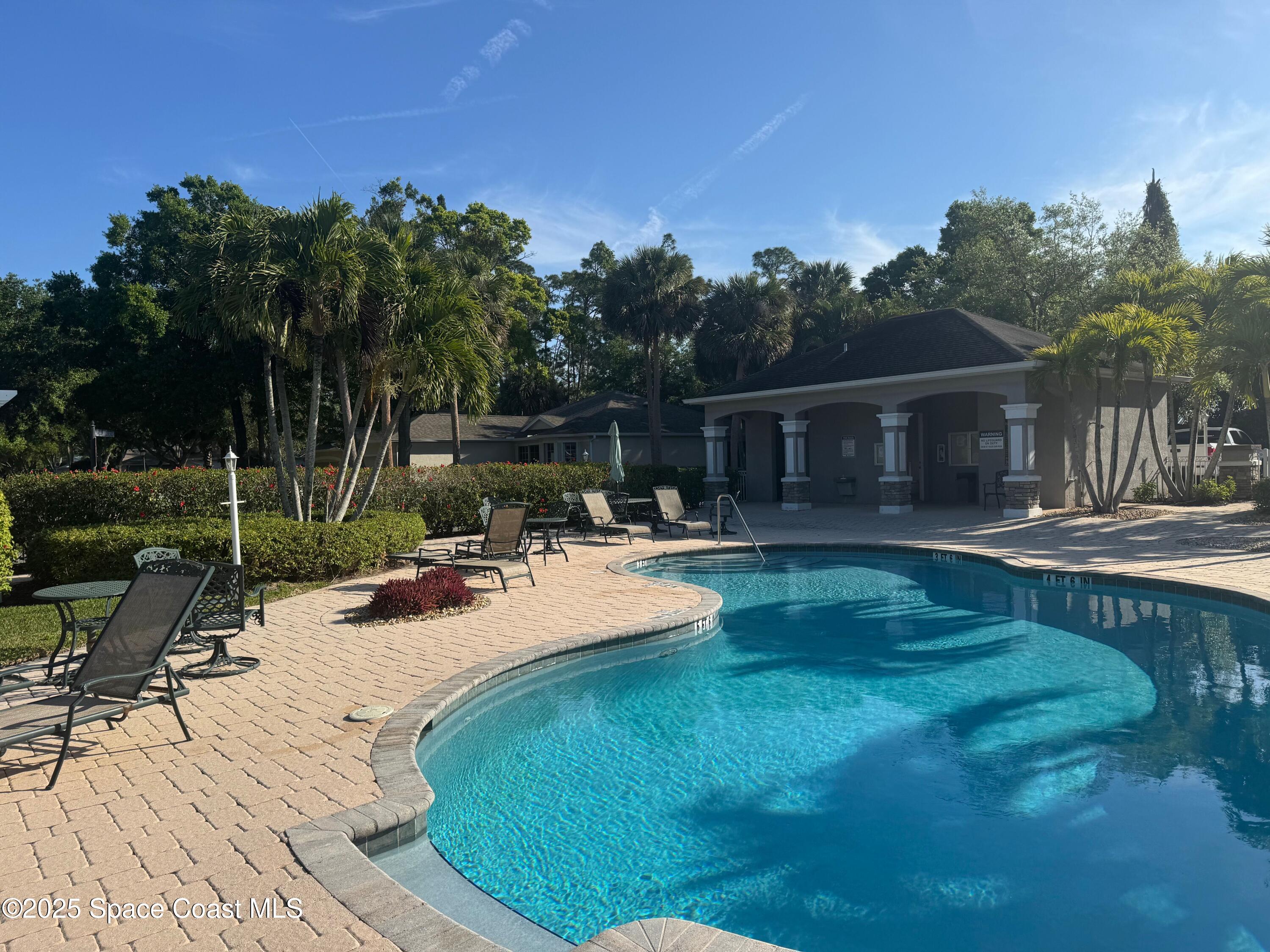 652 Hatteras Court Southwest Vero Beach, FL 32968 - Photo 41 of 48 a view of swimming pool that has lawn chairs with plants and trees
