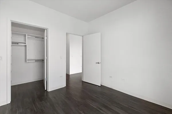 a view of an empty room with wooden floor and closet