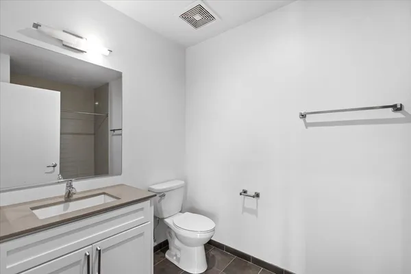 a bathroom with a granite countertop sink toilet and mirror