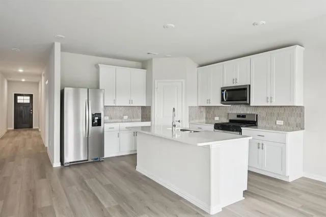 a kitchen with cabinets stainless steel appliances and wooden floor