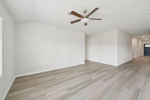 an empty room with wooden floor and a ceiling fan