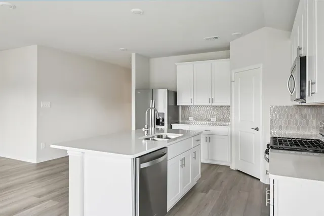a kitchen with a sink cabinets stainless steel appliances and wooden floor